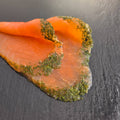 Graved Lachs auf dunklem Schiefer: hauchdünne, von Hand geschnittene Scheiben mit einem Rand aus frischem Dill, nach nordischer Art gebeizt.