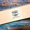 Holzgeschenkbox mit Schiebedeckel, Seilgriff und Logo der Lachs-Räucherei Wortberg auf blauem Holztisch