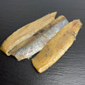 Kaltgeräucherte Matjesfilets auf schwarzem Schiefer, goldfarben mit silbriger Haut.
