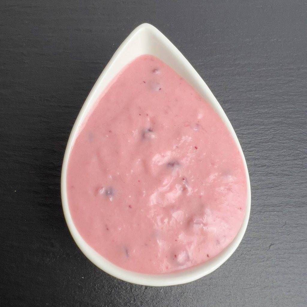 Kronsbeersauce in weißer Schale auf schwarzem Schiefer: rosafarbene Meerrettich-Sahne mit Preiselbeeren.