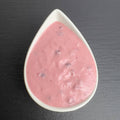 Kronsbeersauce in weißer Schale auf schwarzem Schiefer: rosafarbene Meerrettich-Sahne mit Preiselbeeren.