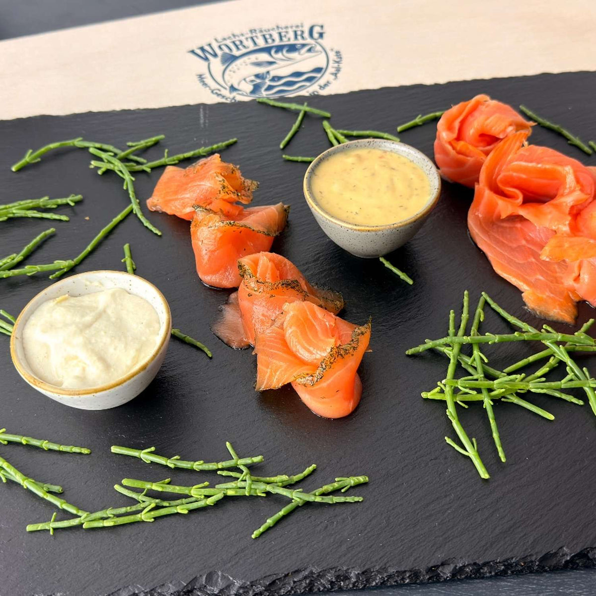 Präsent Küstenschmaus mit Räucherlachs, Graved Lachs, Meerrettich-Sahne-Creme und Senf-Dill-Sauce auf einer Schieferplatte