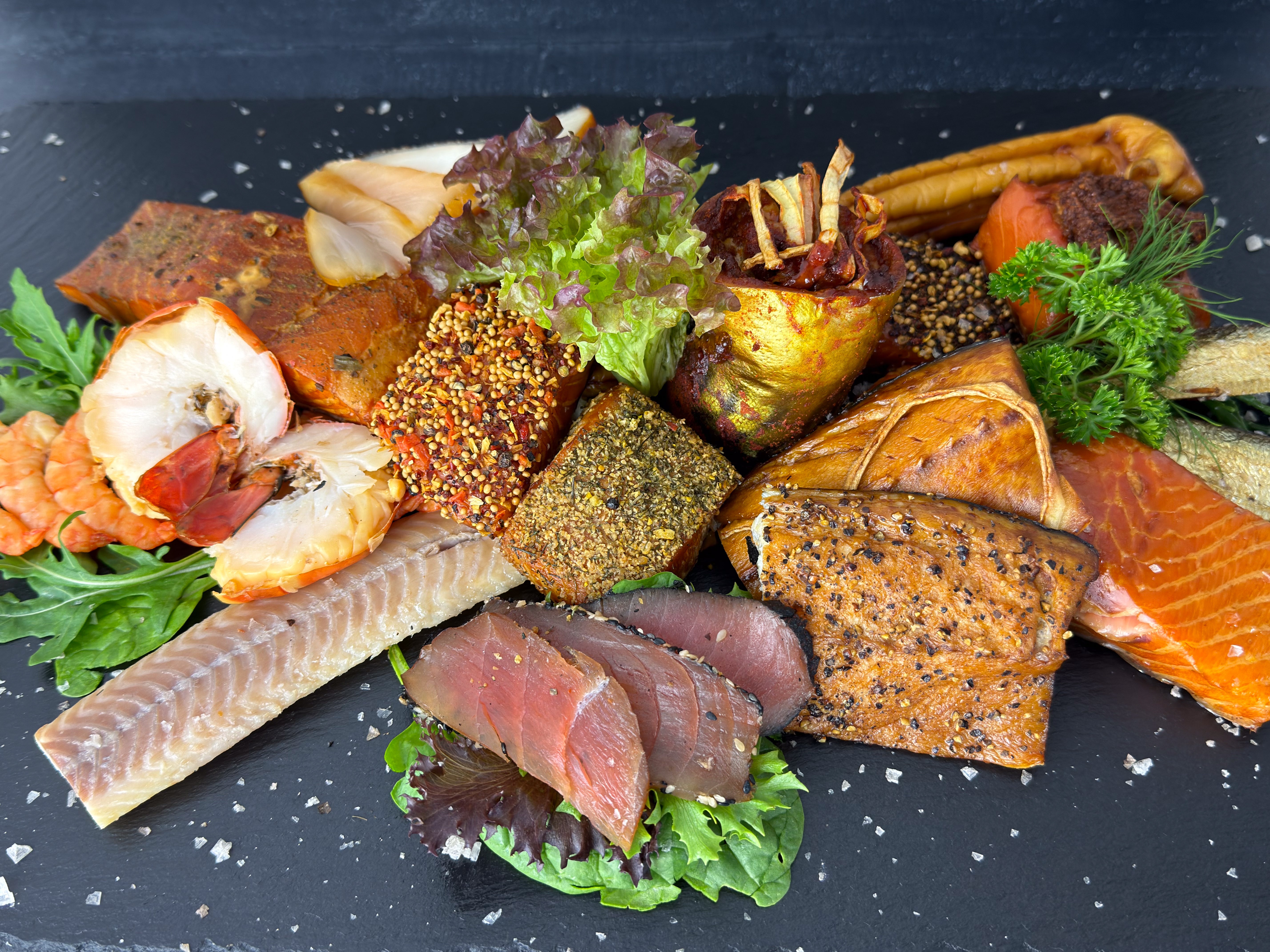 Räucherfisch aus eigener Räucherei auf Schiefer: Lachs mit Gewürzkruste, Pfeffermakrele, Aal, Forellenfilet, geräucherter Thunfisch und Garnelen – Wuppertaler Fischkultur