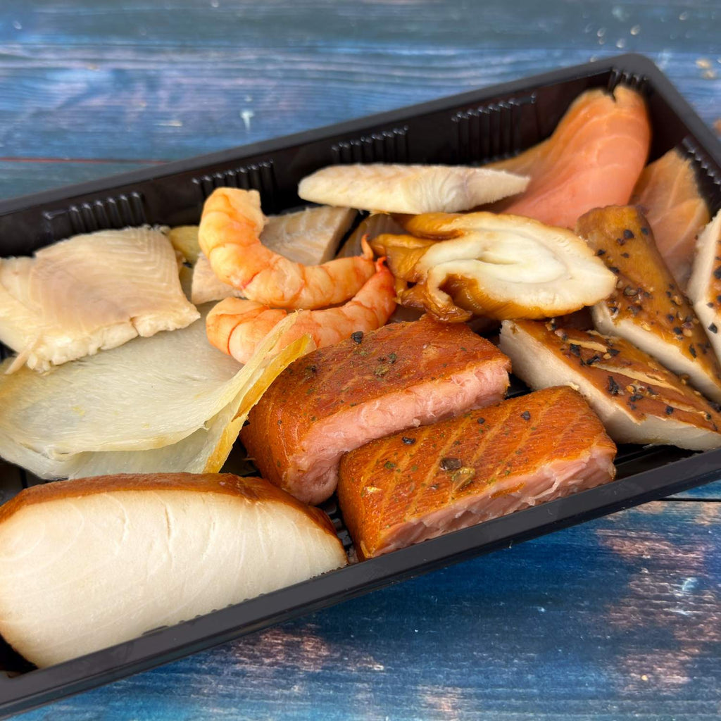 Räucherfisch-Variation in schwarzer Schale: Räucherlachs, Wikinger-Lachs, Aal, Garnelen, Schillerlocke, Makrele mit Pfeffer, Heilbutt und weitere Sorten.