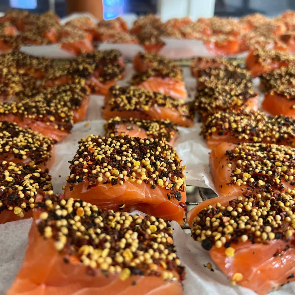 Handarbeit vor dem Räuchern: rohe Lachsstücke mit Kruste aus Senfsaat, Pfeffer und Chili in unserer Räucherei in Wuppertal.