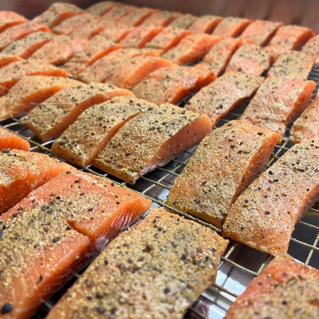 Wikinger-Lachs vor dem Räuchern: rohe Lachsfilets mit Kruste aus Wacholder und Zitronenpfeffer auf dem Rost in unserer Räucherei in Wuppertal.